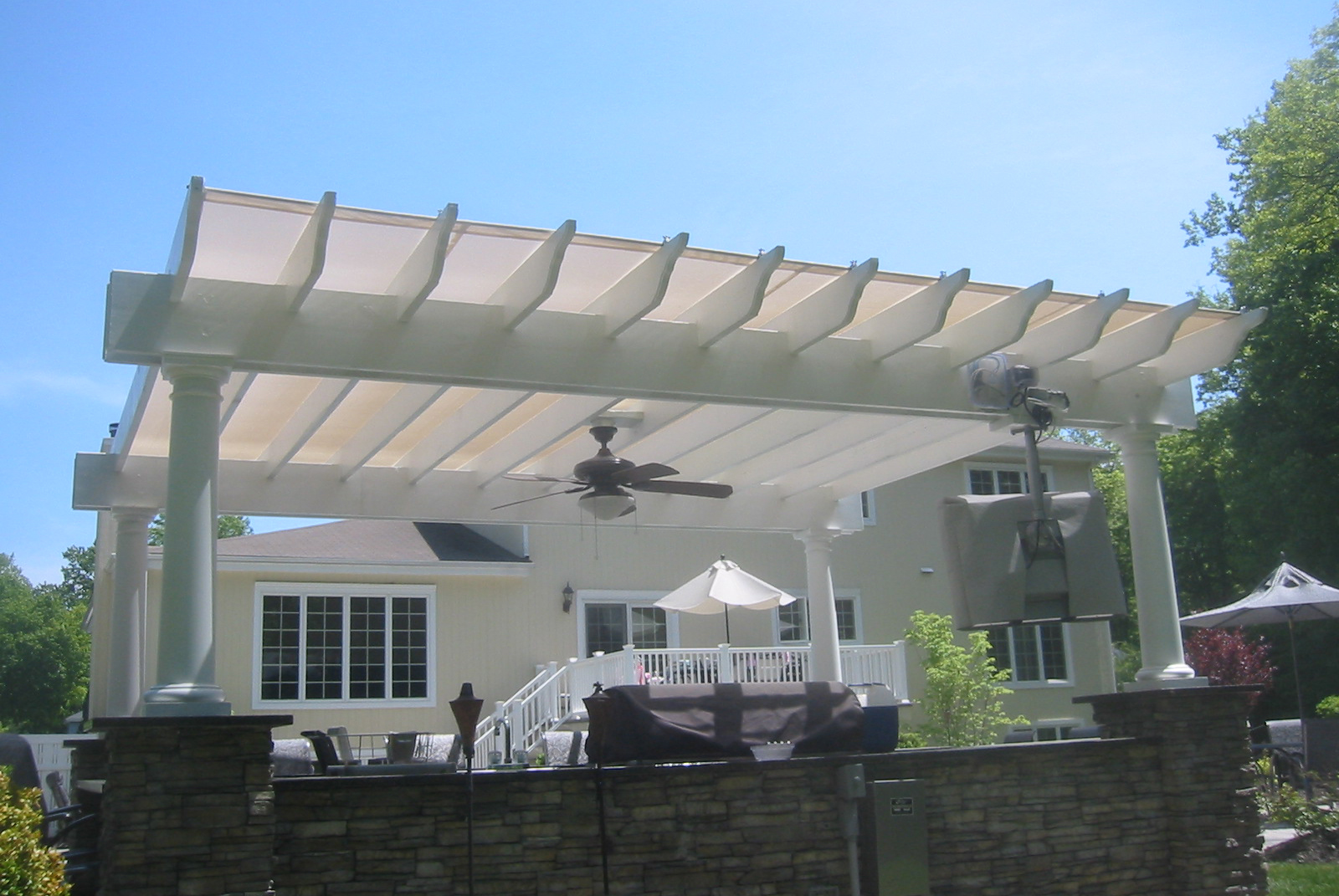 white pergola covering a stand alone outdoor room with amenities
