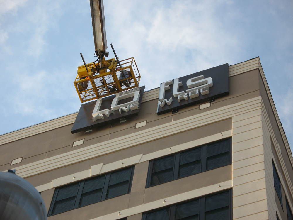a crane being used to install a large sign on the side of a building